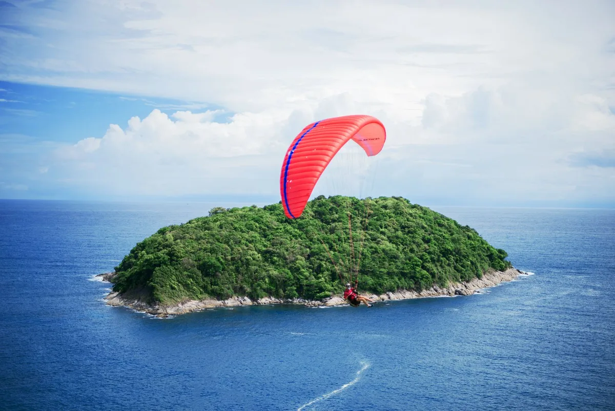 person riding a parachute with a view of blue waters and an island