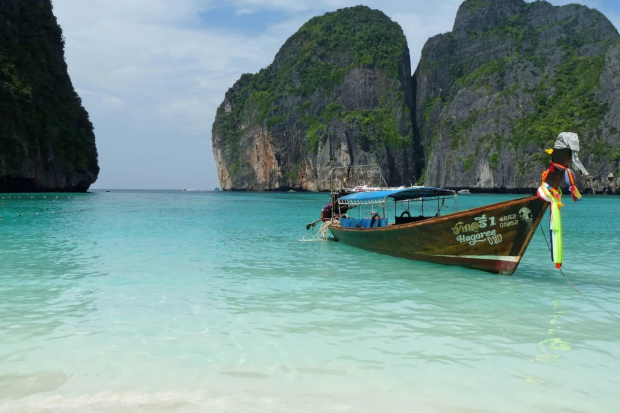 A wooden longtail boat on turquoise water below limestone cliffs at Koh Phi Phi in southern Thailand
